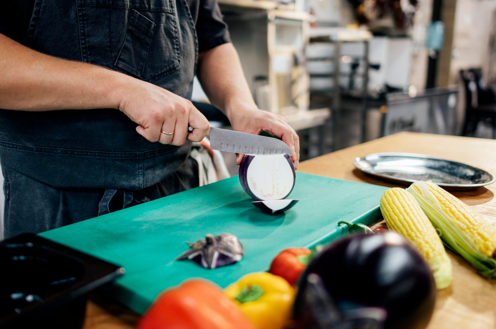 male-chef-slicing-aubergine-kitchen